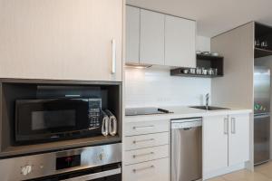 a kitchen with white cabinets and a microwave at Nouvo Apartments in Wellington