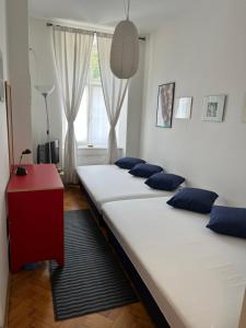 3 camas en una habitación con una mesa roja y una ventana en Home in Krakow Silvio's Apartments, en Cracovia