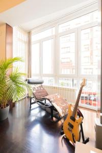 a living room with a guitar and a chair at Frente al parque, en el centro in Bilbao