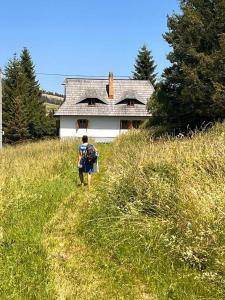 a man walking down a hill in front of a house at Cesta z mesta na Huty in Huty