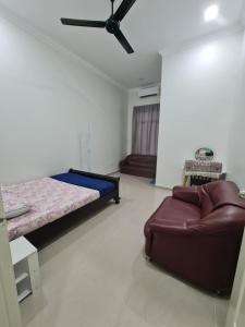a bedroom with a bed and a couch in it at OLIA MEDINA KERTEH 4 BILIK HOMESTaY in Kampong Kemaman