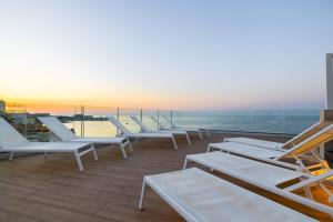 a row of lounge chairs on a balcony with the ocean at The Diplomat Hotel in Sliema