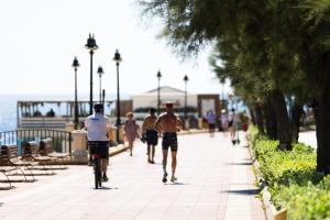 a group of people walking and riding bikes down a sidewalk at The Diplomat Hotel in Sliema