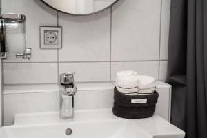 La salle de bains est pourvue d'un lavabo, d'un miroir et de serviettes. dans l'établissement Cozy Apartment in Prime Location with Balcony - Hotel Comfort in 2 Room Apartment in Cologne Neumarkt - City Loft 11 -, à Cologne