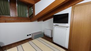 um pequeno quarto com uma televisão e um radiador e um tvictericter em Wine Resort em Faedis