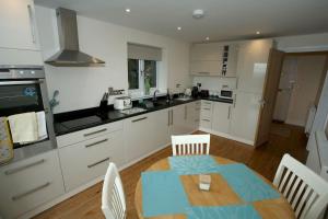 uma cozinha com armários brancos e uma mesa e cadeiras em Lovely two bedroom bungalow with hot tub em Yeovil