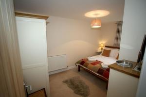 a small bedroom with a bed and a table at Lovely two bedroom bungalow with hot tub in Yeovil
