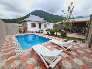 een zwembad met twee witte stoelen en een huis bij Nasimi Villa in Gabala