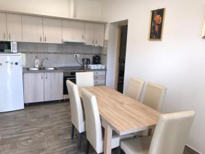 a kitchen with a wooden table and white appliances at Tó-Party Apartman in Kiszombor