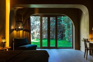 1 dormitorio con una gran puerta de cristal que conduce a un jardín en Life Gallery Hotel, en Korçë