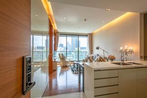 a kitchen with a sink and a living room at Luxury 1Bed 1Bath 300m BTS Phrom Phong, Emporium EmSphere EmQuartier in Bangkok