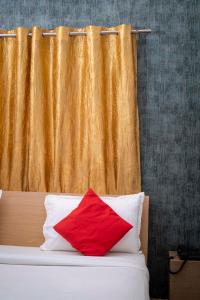 een bed met een rood kussen en een gordijn bij Hotel Town and country inn ( a unit of GS RESIDENCY) in Guwahati