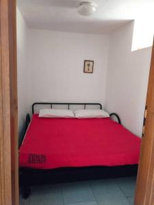 a bedroom with a bed with a red blanket at Appartamento con la vista in Oltre il Colle