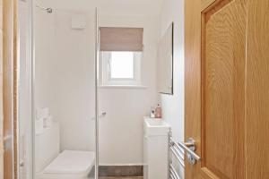 a white bathroom with a toilet and a window at Livestay-Three Bedroom House in Belvedere with Private Garden in Belvedere