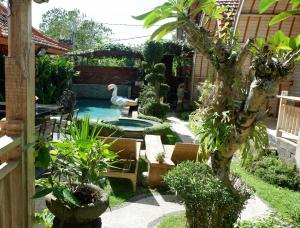 a garden with a pool with a swan in it at Wisnu Lumbung Uluwatu in Uluwatu