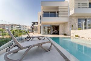 una piscina con una poltrona accanto a una casa di Luxury semidetached villa Smokva 1 - near the center and sea - by TRAVELER tourist agency Krk a Krk