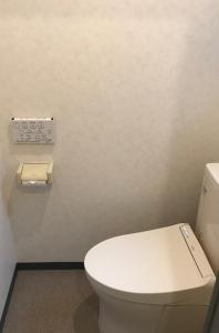 a bathroom with a white toilet and a toilet paper dispenser at Pension Amagiji in Izu