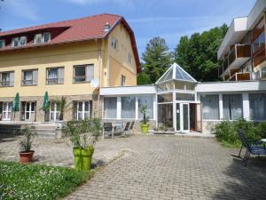 ein Gebäude mit Stühlen und Tischen im Innenhof in der Unterkunft Hotel Kenese in Balatonkenese