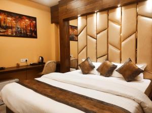 - une chambre avec un grand lit blanc et une tête de lit en bois dans l'établissement Hotel Friends Palace, à Tezpur