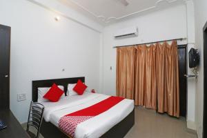 Rudrapur的住宿－OYO Flagship 24199 Hotel Mid Town Ojus Tower，一间卧室配有一张带红色枕头的大床