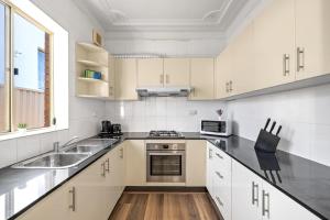 a white kitchen with a sink and a stove at Comfort Queen Room - Private - Prime Spot in Sydney