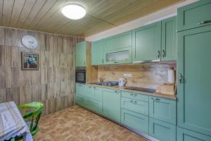 a kitchen with green cabinets and a clock on the wall at Wellness House On The River Kupa - Happy Rentals in Banska Selnica