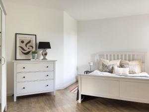 a white bedroom with a bed and a dresser at Home by Doni - zentral I Parkplatz I Küche I Balkon in Bielefeld