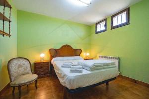 ein Schlafzimmer mit einem Bett und einem Stuhl sowie zwei Fenstern in der Unterkunft El Collao de Nuño in Gijón