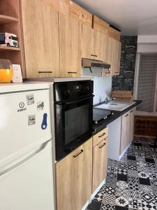 a kitchen with a white refrigerator and a black and white floor at Petite maison sympa in Saint-Jean-sur-Mayenne