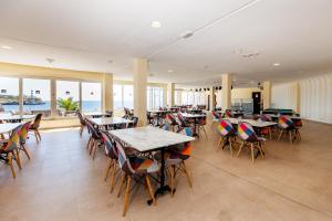 a restaurant with tables and chairs and the ocean at Bellevue Belsana in Portocolom