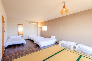 Habitación con 3 camas y alfombra. en 南知多Seaside Villa en Minamichita