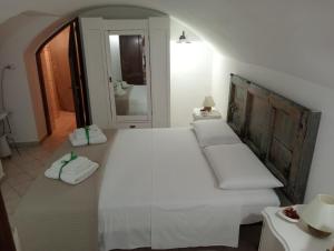 1 dormitorio con 1 cama blanca grande y espejo en Maison Chèrie, en Parabita