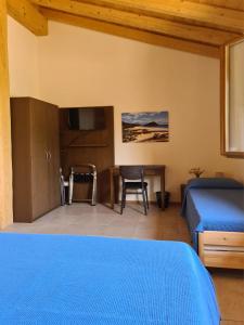 1 dormitorio con cama azul y escritorio en Agriturismo Corte degli Ulivi, en Capoterra