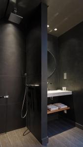 a black bathroom with a shower and a sink at Hotel de Nell in Paris