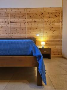 1 dormitorio con cama azul y pared de madera en Agriturismo Corte degli Ulivi, en Capoterra