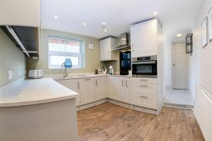 a kitchen with white cabinets and a wooden floor at Apartment West in Whitby