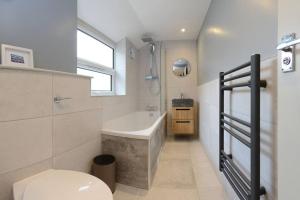 a bathroom with a tub and a toilet and a sink at Apartment West in Whitby
