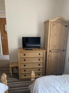 um quarto com uma cómoda e uma televisão em Oakwell Guest House em Bridlington