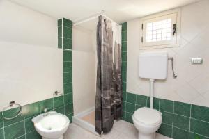 a green and white bathroom with a toilet and a shower at Casa Isabella in Budoni