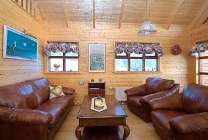 a living room with leather couches and a coffee table at Gljúfurbústaðir Holiday Homes in Hveragerði