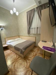 a bedroom with a bed and a desk and a chair at Grand Christer Hotel in Kyiv