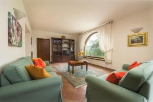 ein Wohnzimmer mit 2 grünen Stühlen und einem Tisch in der Unterkunft FONTE PINELLA 8, Emma Villas in Chiusi