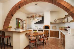 a kitchen with an archway and a wooden table at FONTE PINELLA 8, Emma Villas in Chiusi