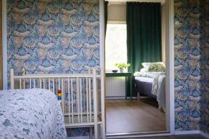 a bedroom with a crib and a wall with a floral wallpaper at Norrby Residence,my vintage bnb 