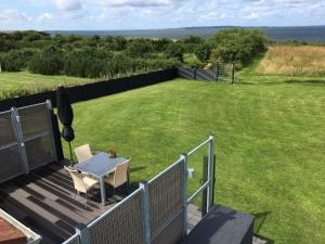 a deck with a table and a field of grass at Casa Uno North - Nice appartement for two with sea view in Farsø