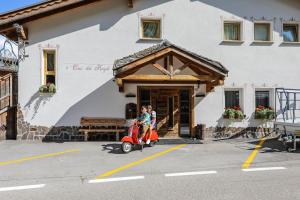 zwei Kinder, die mit einem Roller vor einem Gebäude fahren in der Unterkunft Cesa dele Angele in Colle Santa Lucia