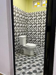 a bathroom with a toilet in a black and white tile floor at Perhentian Mama's in Perhentian Islands