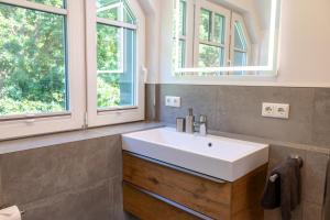 a bathroom with a white sink and two windows at Lieblingshof in Born