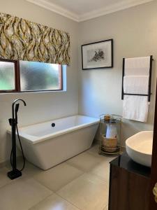 Baño blanco con bañera y lavamanos en The Woodpecker Inn, en Pretoria