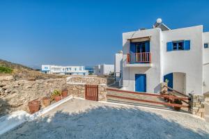 a white house with blue doors and a stone wall at Lovely Apartment With Shared Pool in Aspro Chorio Paros